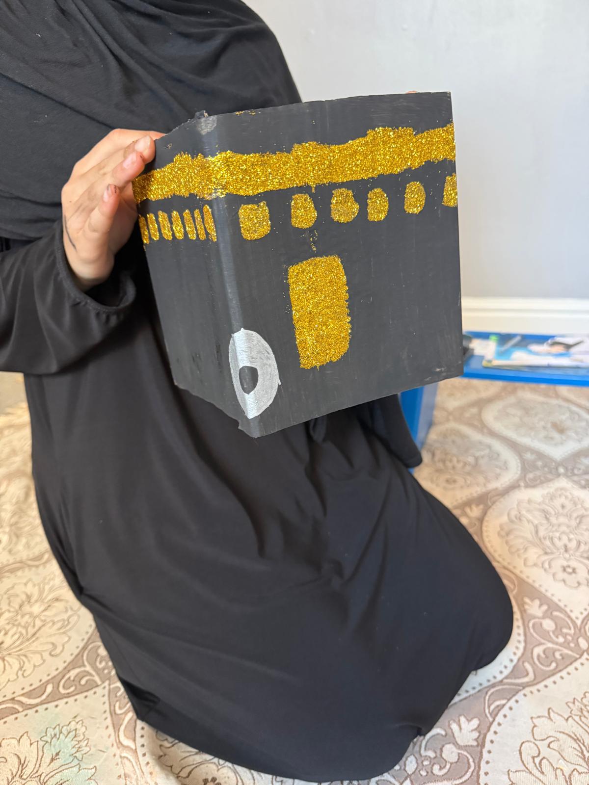 Child holding Kaaba model